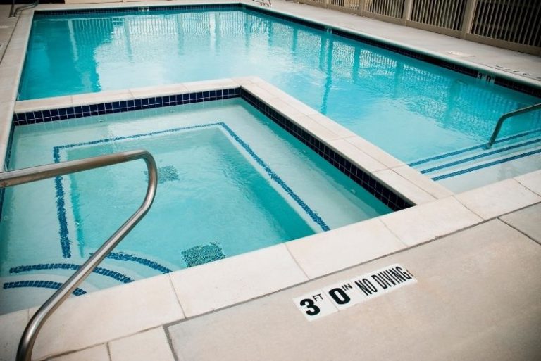 Rectangular swimming pool with attached spa, tiled steps and stainless handrails